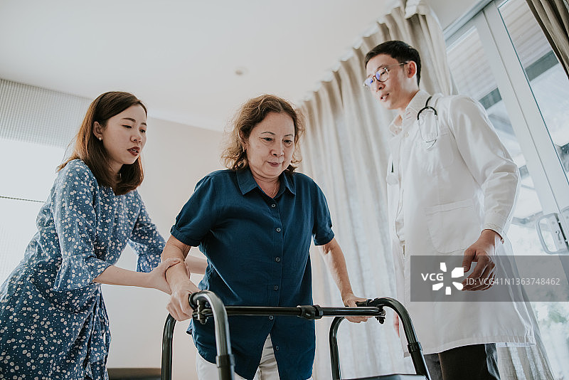 医生和亚裔女儿帮助她的母亲在家使用助行器图片素材