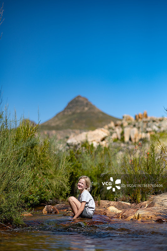 快乐的可爱女孩在炎热的夏日里在荒野的新鲜山涧中玩耍图片素材
