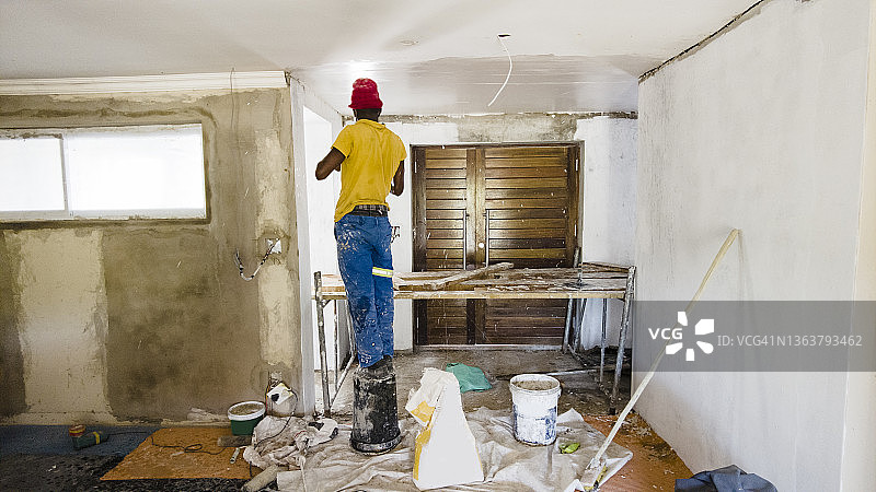 建筑工人在房屋翻新期间粉刷天花板的背面视图图片素材