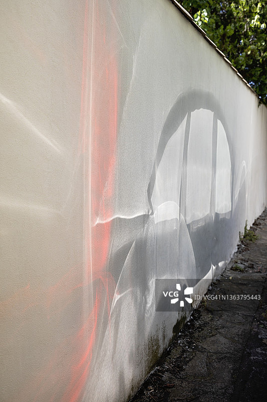 阳光的光电效应：停放的汽车反射到附近的白色墙壁上图片素材