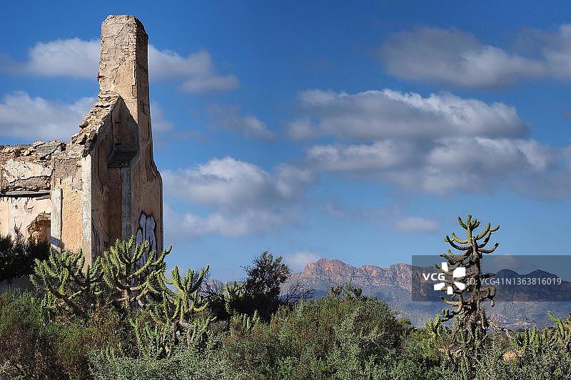 被仙人掌环绕的遗址，可欣赏阿吉隆山的景色，位于西班牙穆尔西亚科科多雷斯的废弃房屋图片素材