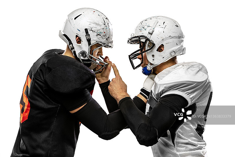 比赛开始前，美式橄榄球运动员在草地上白色背景前对峙的特写图片素材