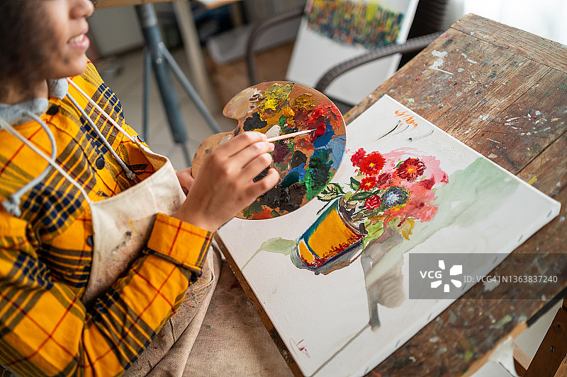 非洲裔女艺术家绘画特写：艺术家手持调色板在画布上绘画图片素材