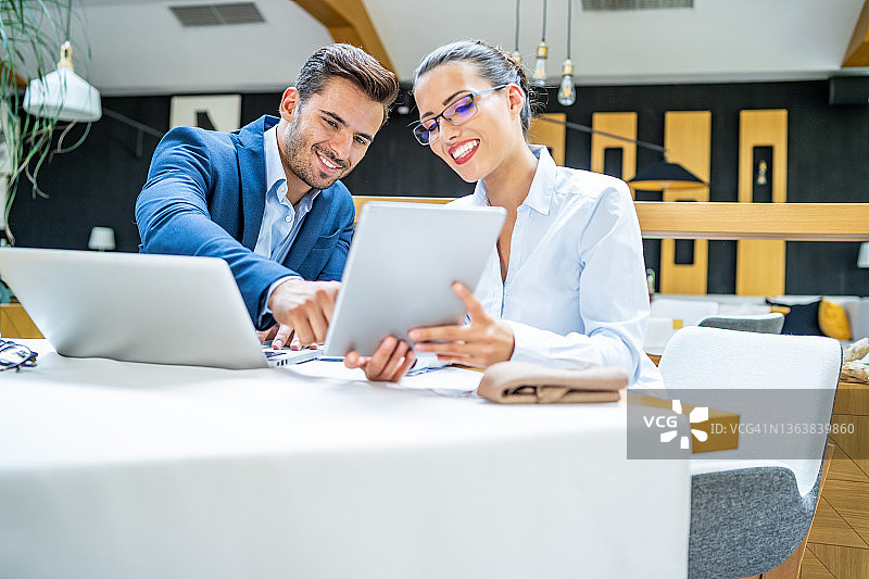 商务人士在餐厅开会午餐，使用笔记本电脑和平板电脑上网，讨论商务解决方案图片素材