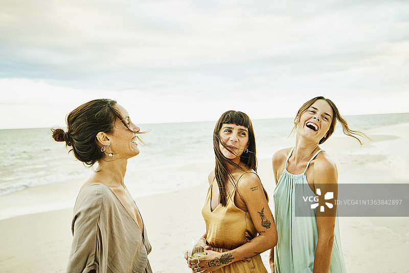 热带度假村日落时分在海滩上放松的微笑女性朋友特写图片素材