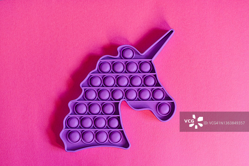 粉色背景上的按压橡胶泡泡的玩具图片素材