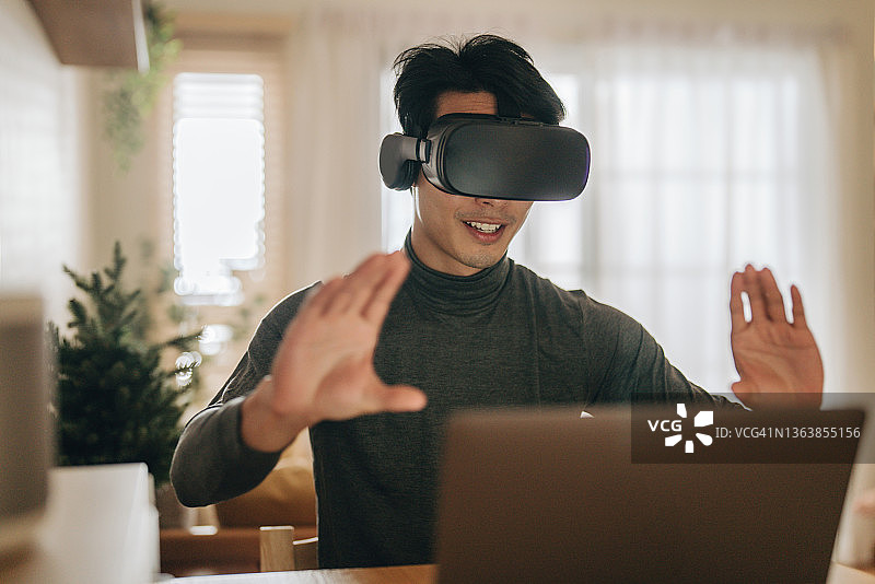 亚洲男人在家戴VR眼镜工作图片素材