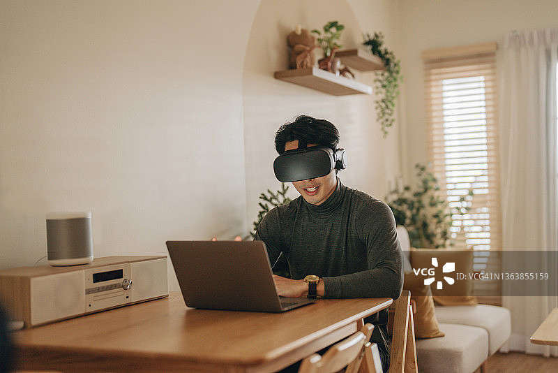 亚洲男人在家戴VR眼镜工作图片素材