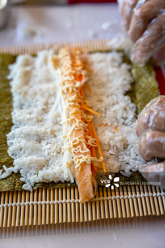 用竹席卷寿司的手部特写图片素材