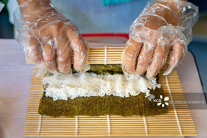 用竹席卷寿司的手部特写图片素材