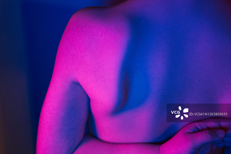 霓虹灯光下的年轻男孩背部特写图片素材