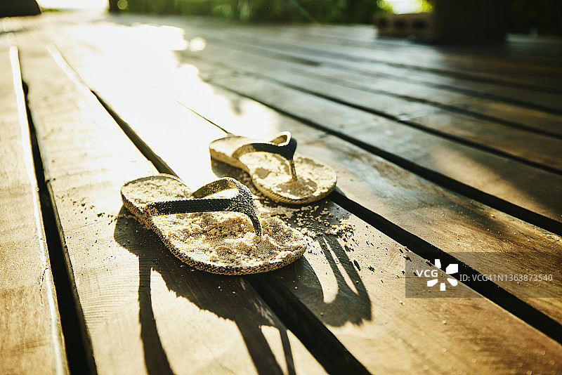 热带别墅甲板上被沙子覆盖的凉鞋图片素材