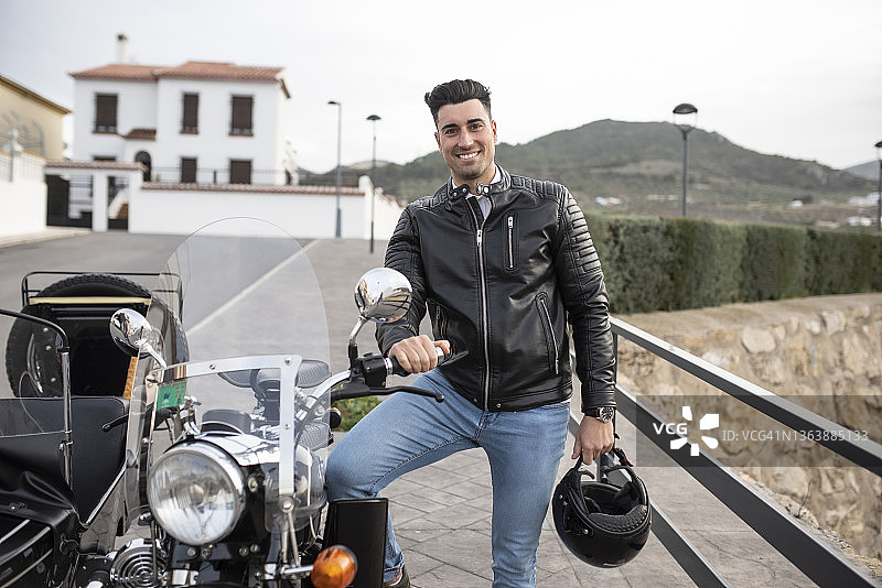 男人在侉子摩托车旁对着镜头微笑，独自旅行图片素材