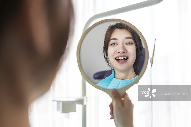 在牙医诊所的镜子中微笑的年轻女人图片素材
