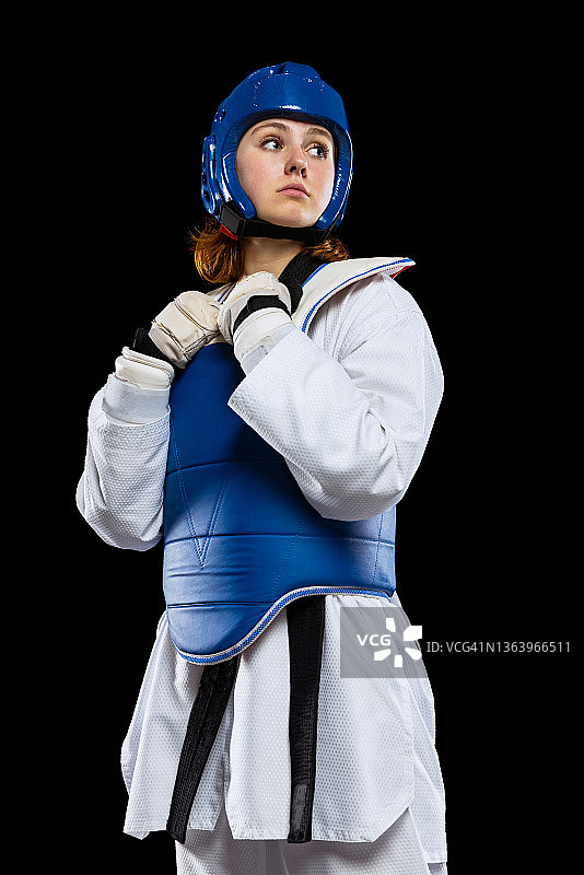 年轻女孩肖像：跆拳道练习者在深色背景下摆姿势，运动技能概念图片素材