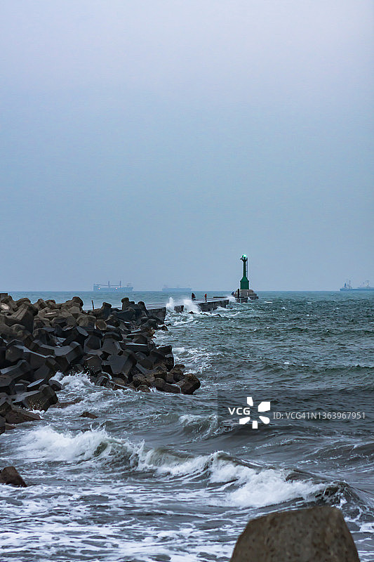 暴风雨前的绿色灯塔，人们在恶劣天气下于廊桥上钓鱼图片素材