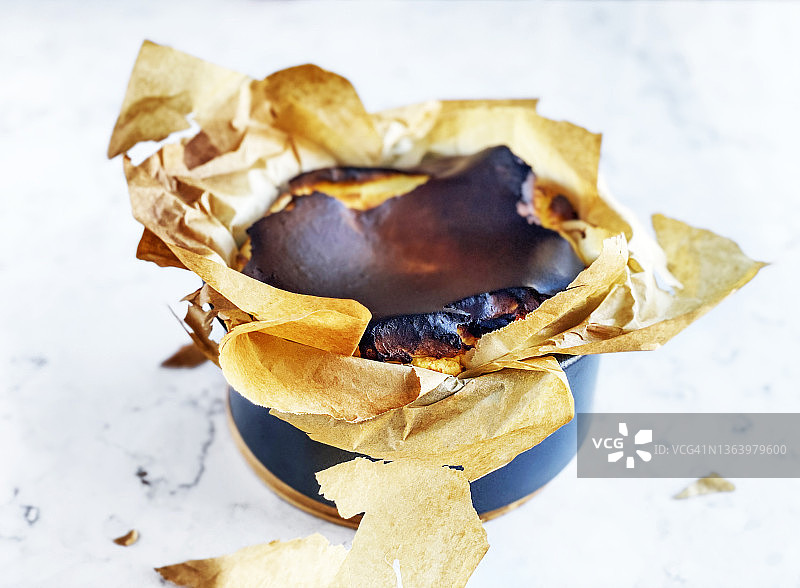 白色大理石背景上的焦香巴斯克芝士蛋糕图片素材