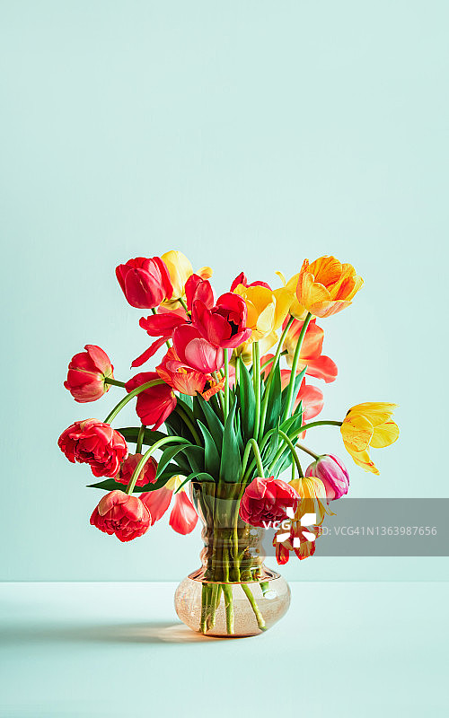 多种颜色郁金香的大花束，在浅绿色背景的复古玻璃花瓶中，含文案空间。商务卡。邀请明信片。国际假日banner图片素材