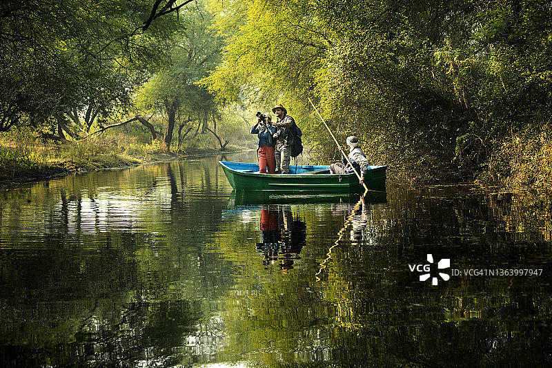 在森林中，乘坐湖上划艇欣赏风景和拍照的夫妇图片素材