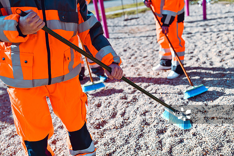 在操场上用扫帚清扫沙子的男性工人图片素材