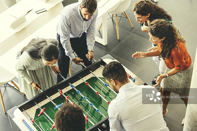 办公室里玩桌上足球的商务人士图片素材