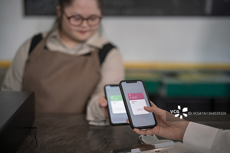 在咖啡店工作，收发手机支付的唐氏综合征患者图片素材