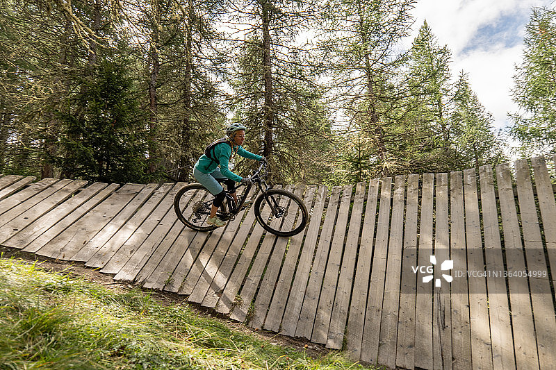 骑山地自行车的女人在夏季的极限木栈道上骑行图片素材