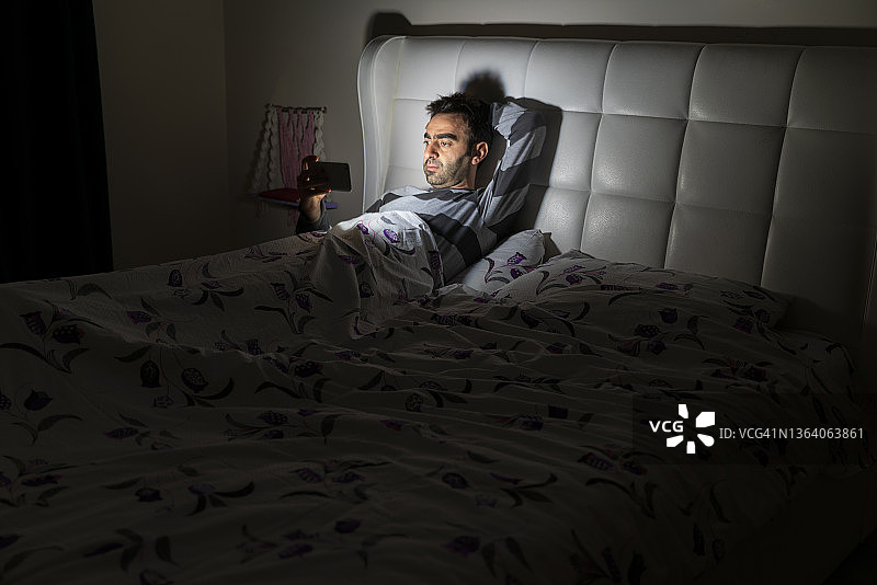 躺在床上用手机看电影的男人图片素材