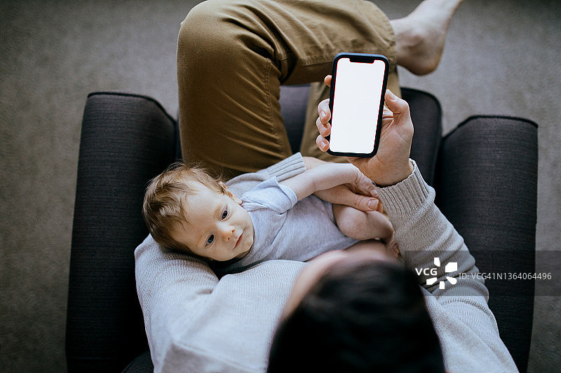 父亲抱着婴儿使用智能手机图片素材