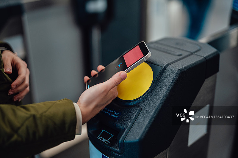 年轻女人在地铁站门口用智能手机进行非接触式支付的特写镜头图片素材