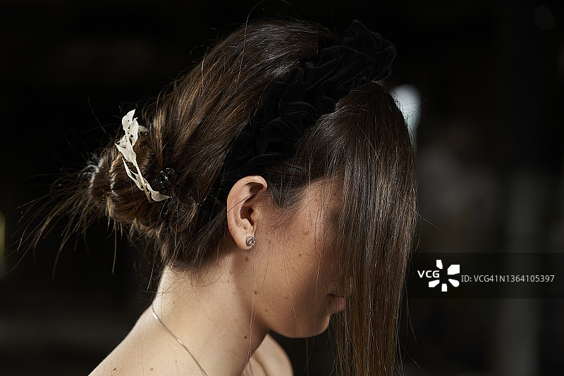 老旧建筑走廊里用头发遮面的棕发年轻白人女性侧脸特写图片素材