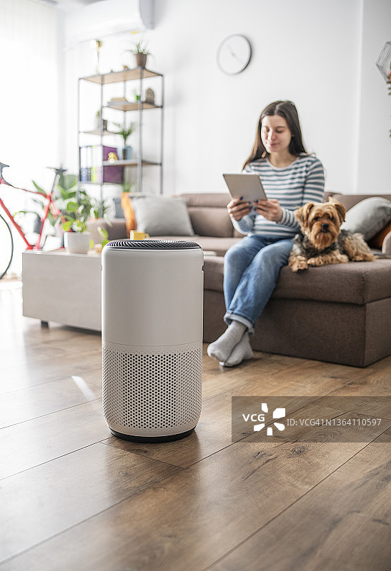女人使用智能系统调节家用空气净化器图片素材