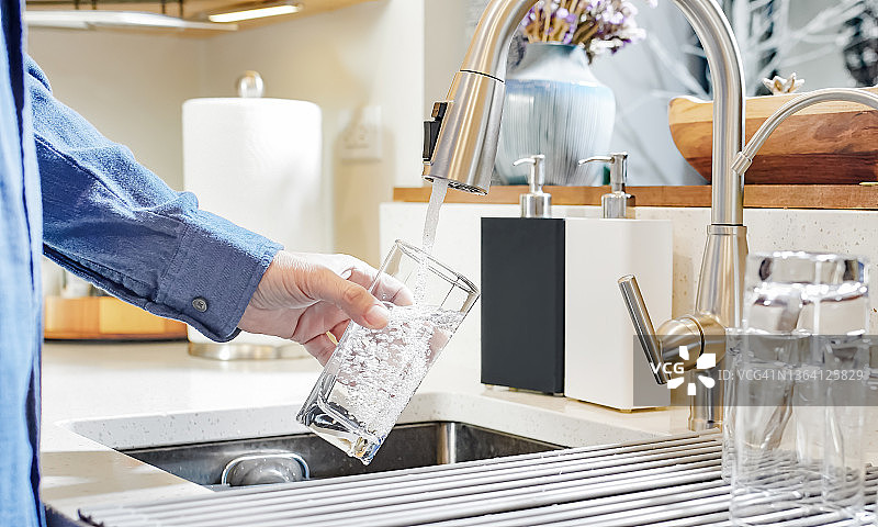 一名男子从厨房水龙头接水图片素材
