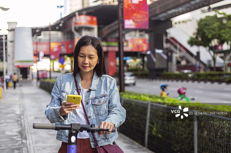 在城市里用智能手机租用电动滑板车的女人图片素材