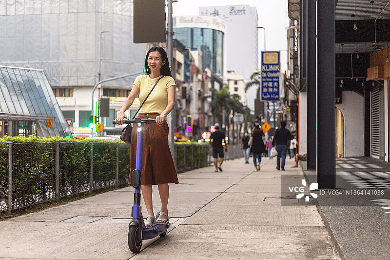 女通勤者在市中心骑电动滑板车图片素材