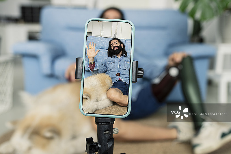 男博主看着手机讲话，装有假肢图片素材