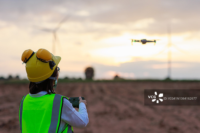 女工程师使用无人机进行风力涡轮机农场的俯视检查图片素材