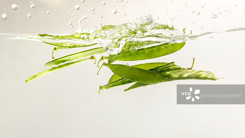 白色背景上水中飞溅的雪豆图片素材