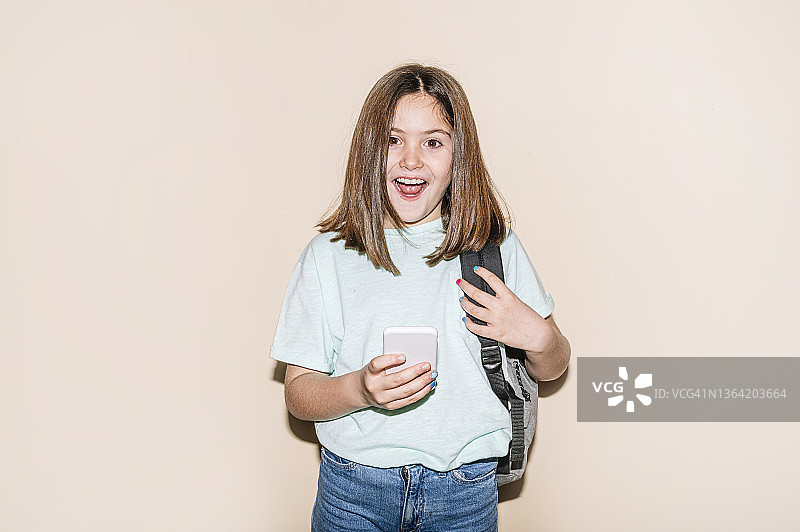 戴着耳机使用智能手机的小女孩图片素材