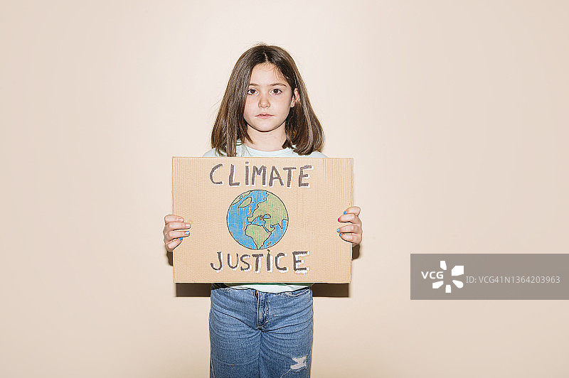 小女孩举着写有“气候正义”的纸板标志图片素材