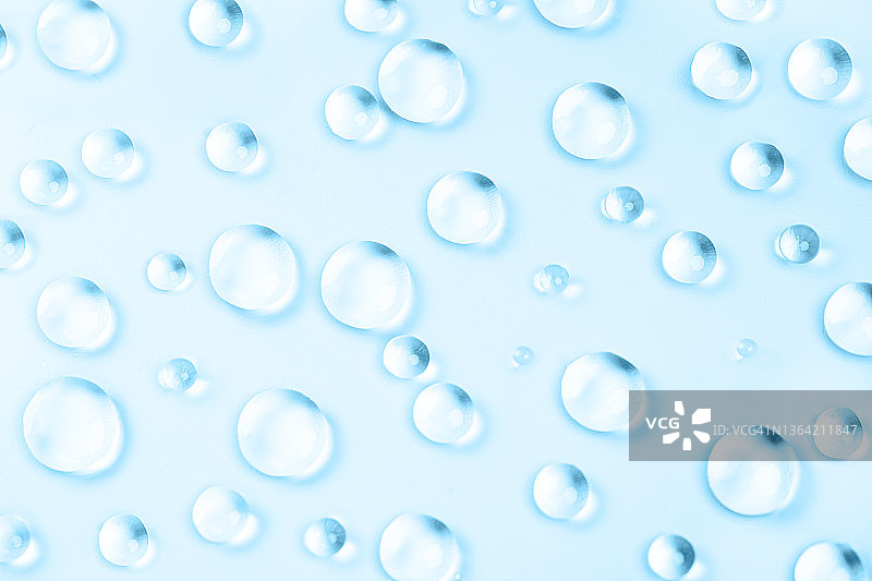 淡蓝色背景上的美容化妆品面部精华、凝胶和精油滴图片素材