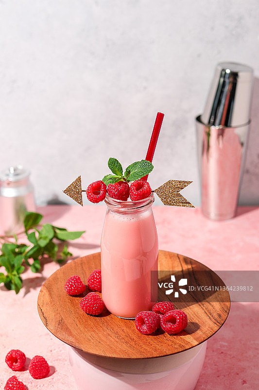 情人节粉色覆盆子奶昔与新鲜水果和丘比特之箭图片素材