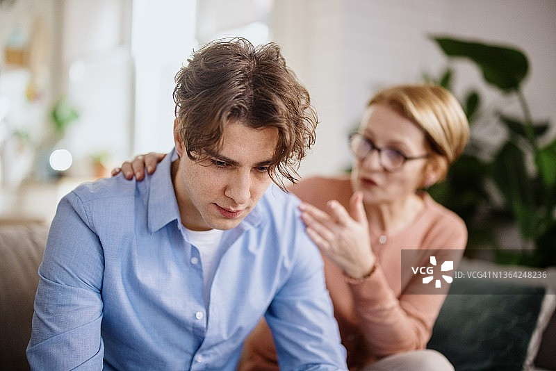 母亲安慰性地拍了拍儿子的背图片素材