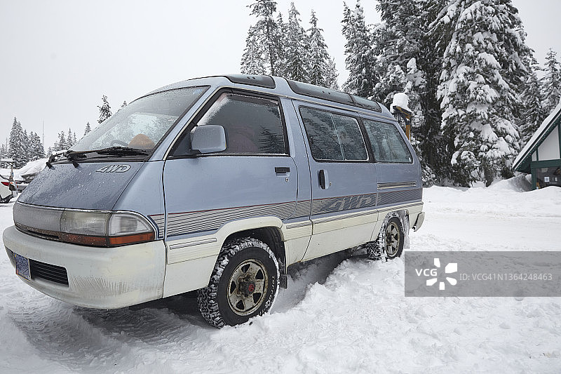 停在雪地街道上的轮胎上装有链条的复古右舵面包车仰视角度照片图片素材