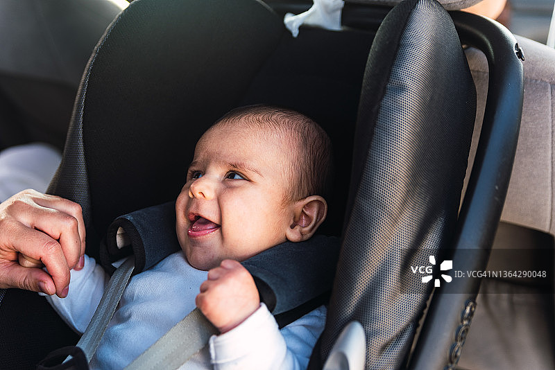 母亲安慰坐在汽车安全座椅上的宝宝图片素材