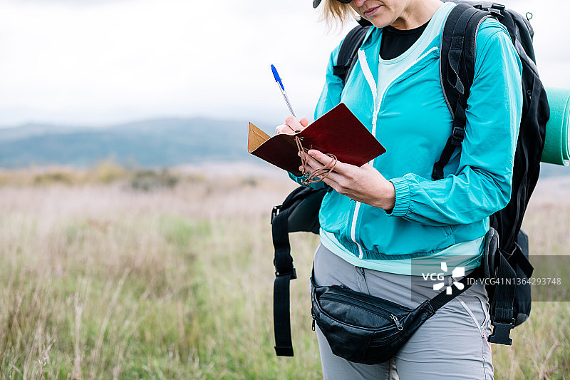 在乡村风景中做笔记的女性背包客图片素材