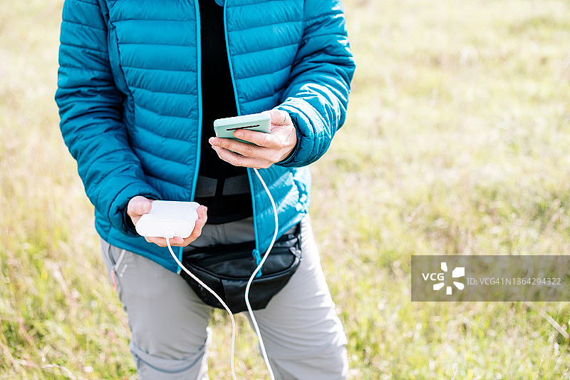 模糊女子在户外拿着连接到充电宝的手机图片素材