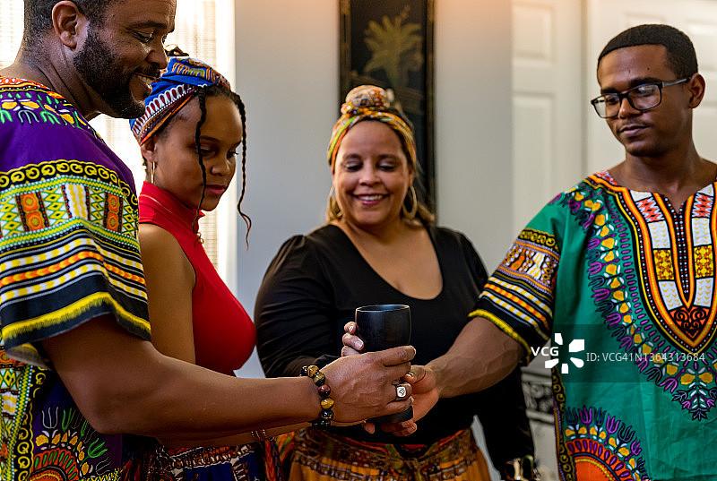宽扎节庆祝活动：非裔美国家庭在家中一起手持团结杯，旁边是Kinara图片素材