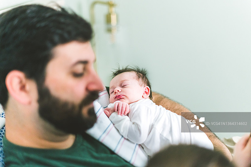 新手父亲在家中抱着新生儿，现代男子气概图片素材