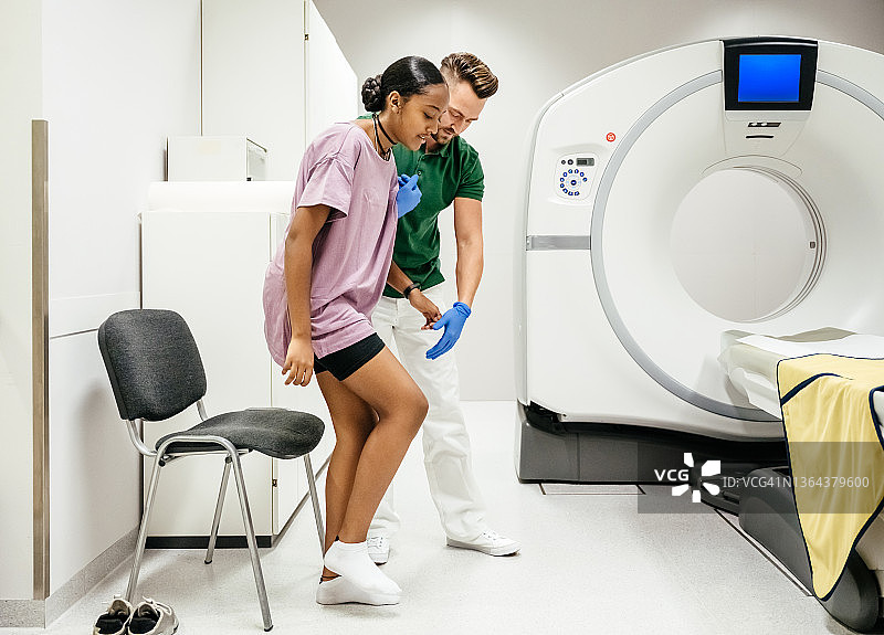 CT技术员帮助受伤患者走向扫描床图片素材